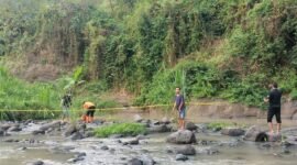petugas dibantu warga hendak mengevakuasi mayat korban 
