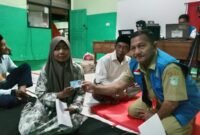 Petugas Dispendukcapil saat menyerahkan KTP salah satu pengungsi