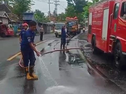 Petugas Damkar ketika melakukan pembersihan tumpahan solar jalur Pasirian Lumajang