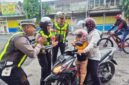 Petugas Satlantas Polres Lumajang saat menyapa pengendara motor tertib berlalu lintas dengan memberikan bunga