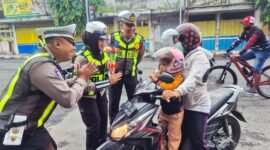 Petugas Satlantas Polres Lumajang saat menyapa pengendara motor tertib berlalu lintas dengan memberikan bunga