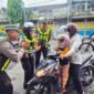 Petugas Satlantas Polres Lumajang saat menyapa pengendara motor tertib berlalu lintas dengan memberikan bunga